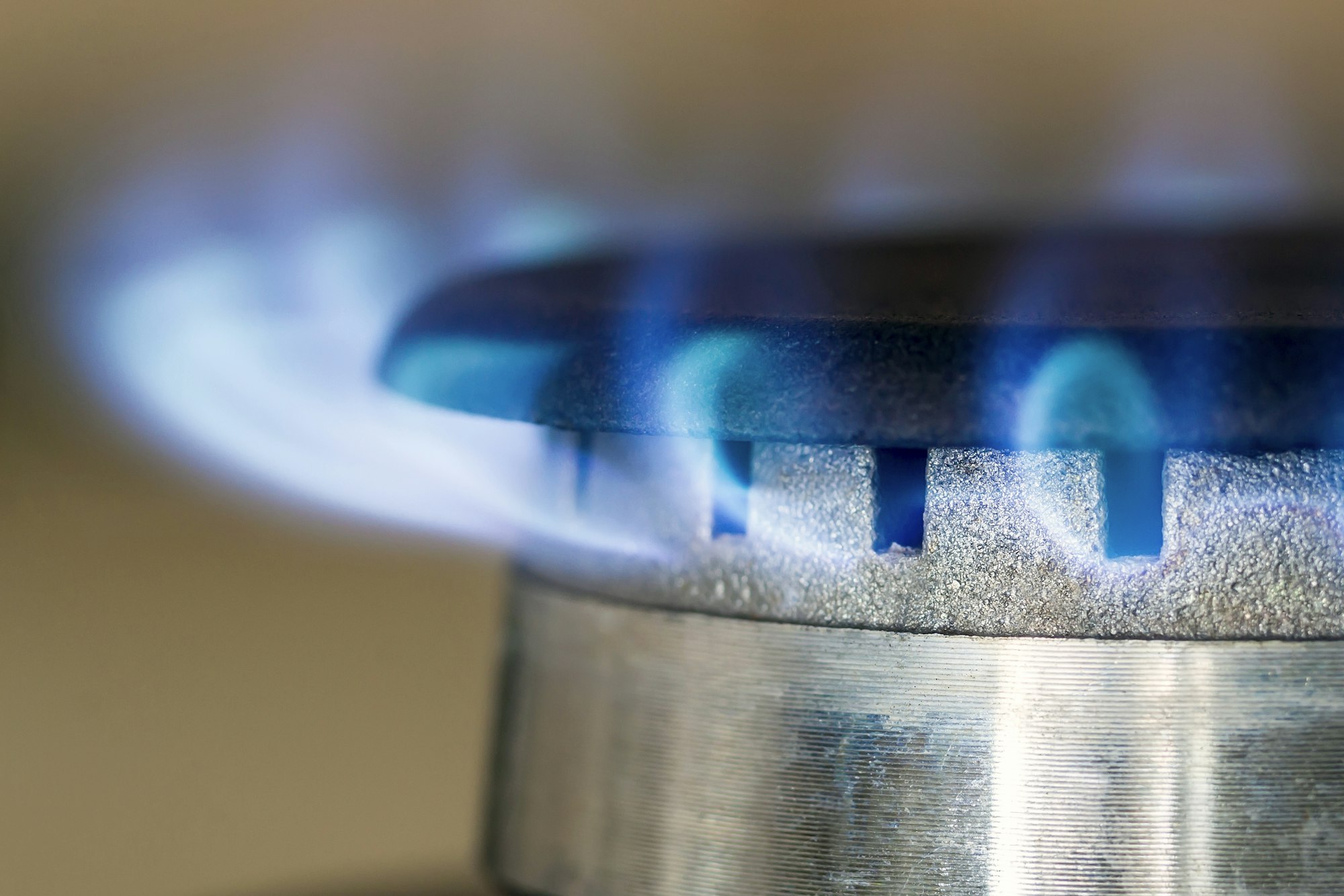 Natural gas blue flames burns on the kitchen stove hob, close up photo with shallow DOF